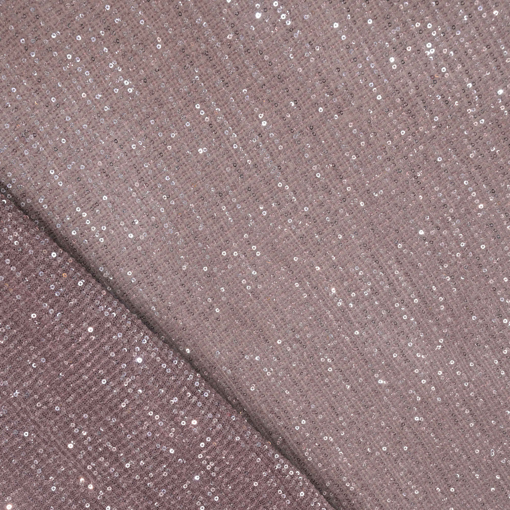 Close-up of a fabric with glittery sequins on a brown background
