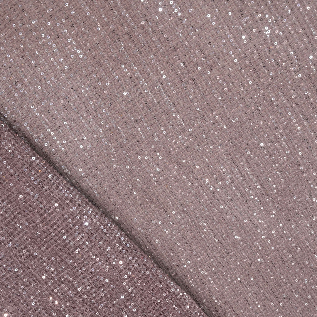 Close-up of a fabric with glittery sequins on a brown background