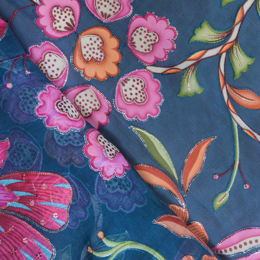Close-up of floral fabric with pink flowers and green leaves on a blue background